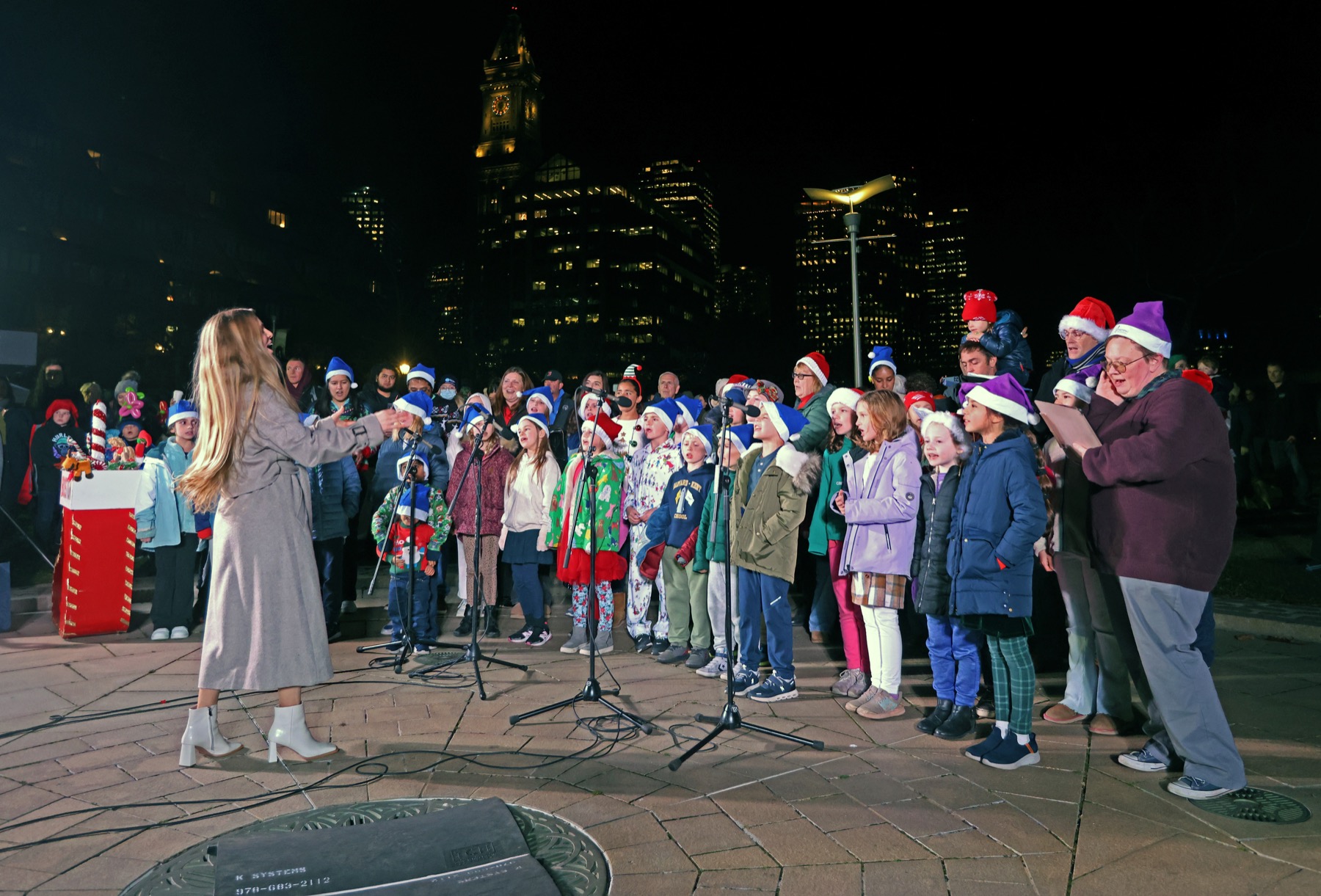 Anna conducting a large outdoor community choir with children and adults