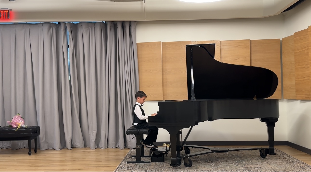 Young piano student performing at a grand piano